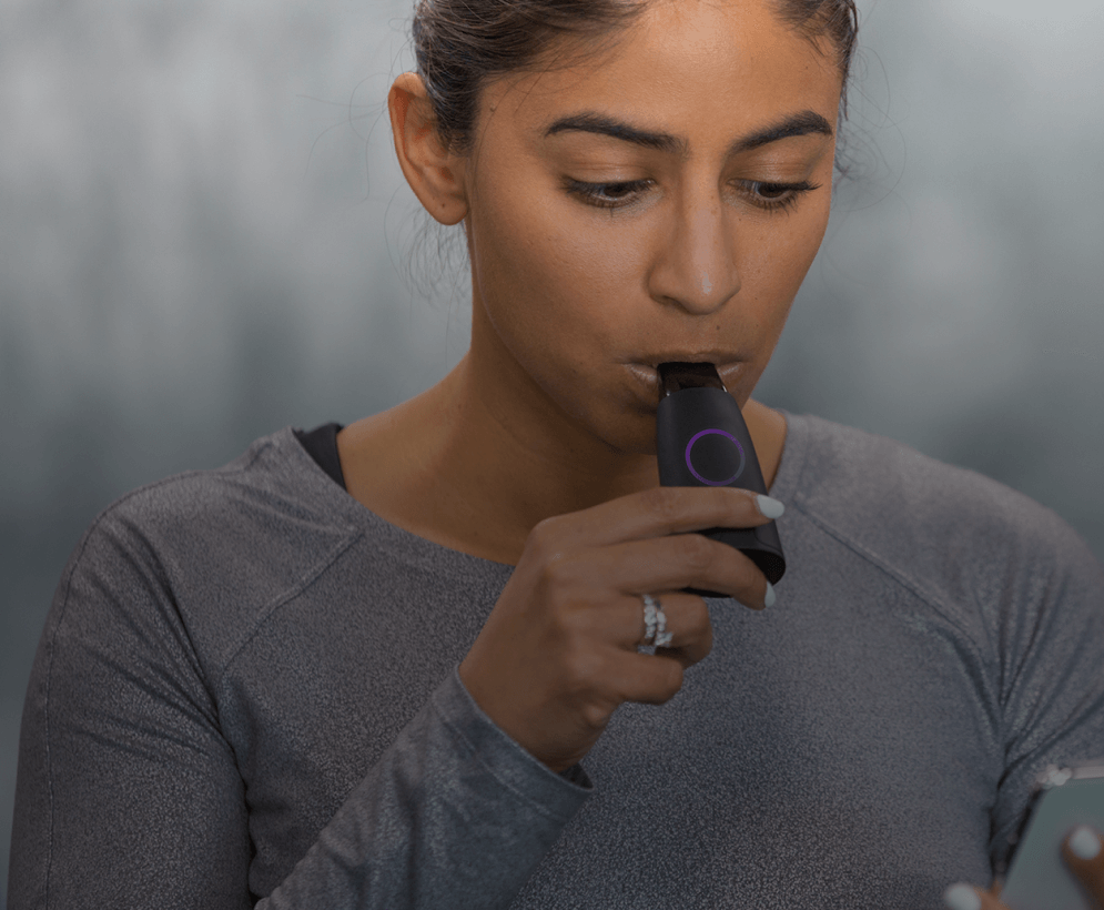 Woman breathing into a Lumen device