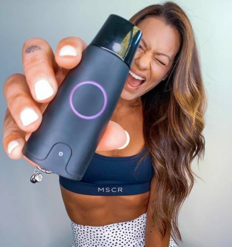 A woman winks and holds a Lumen device